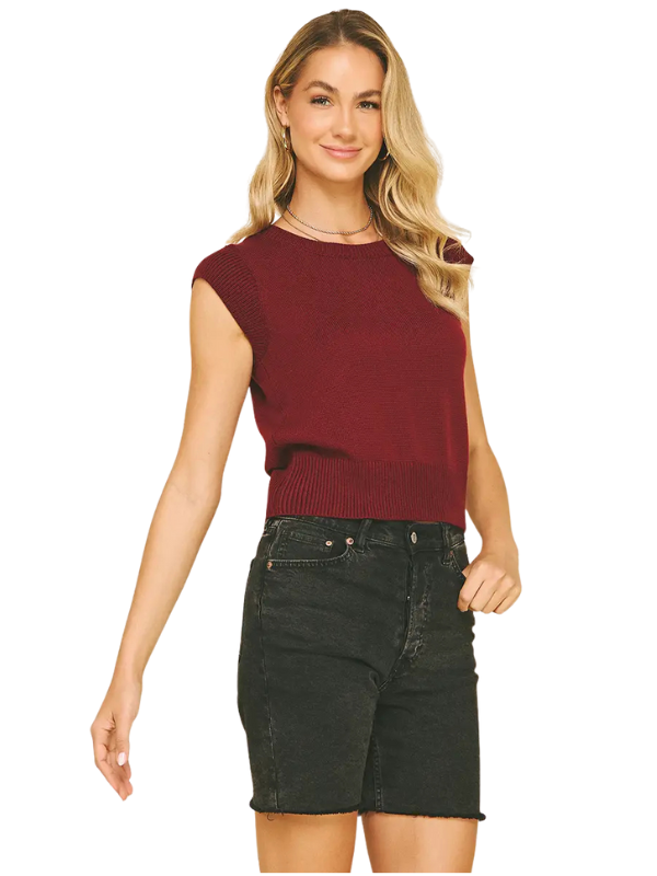 Woman wearing a red sleeveless top and black shorts on a white background