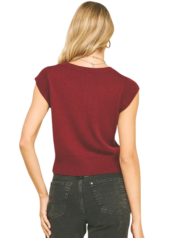 Woman wearing a burgundy sweater and dark jeans on a white background