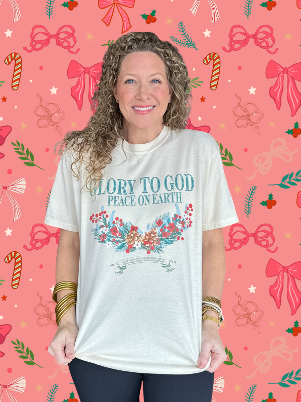 Woman wearing a white t-shirt with Christmas-themed text and graphics on a festive background.