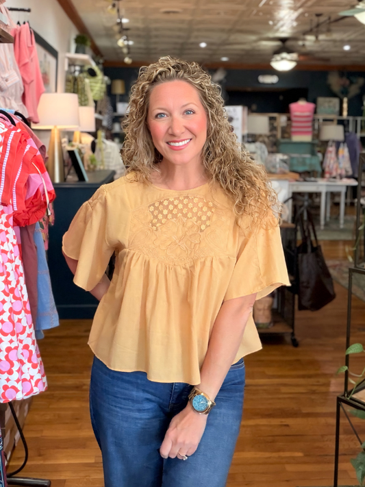 Woman wearing a yellow blouse and blue jeans in a store setting