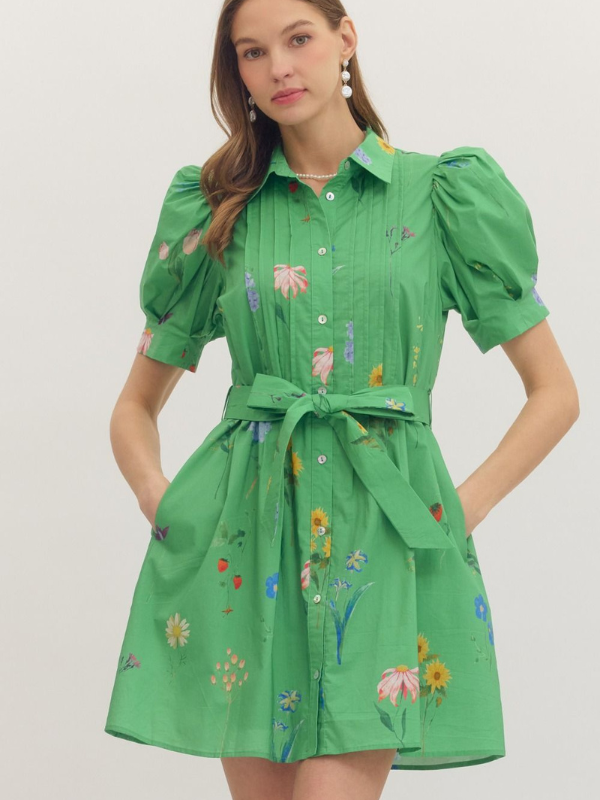 Woman wearing a green dress with floral patterns on a plain background