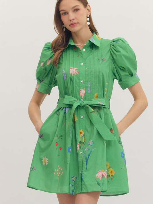 Woman wearing a green dress with floral patterns on a plain background