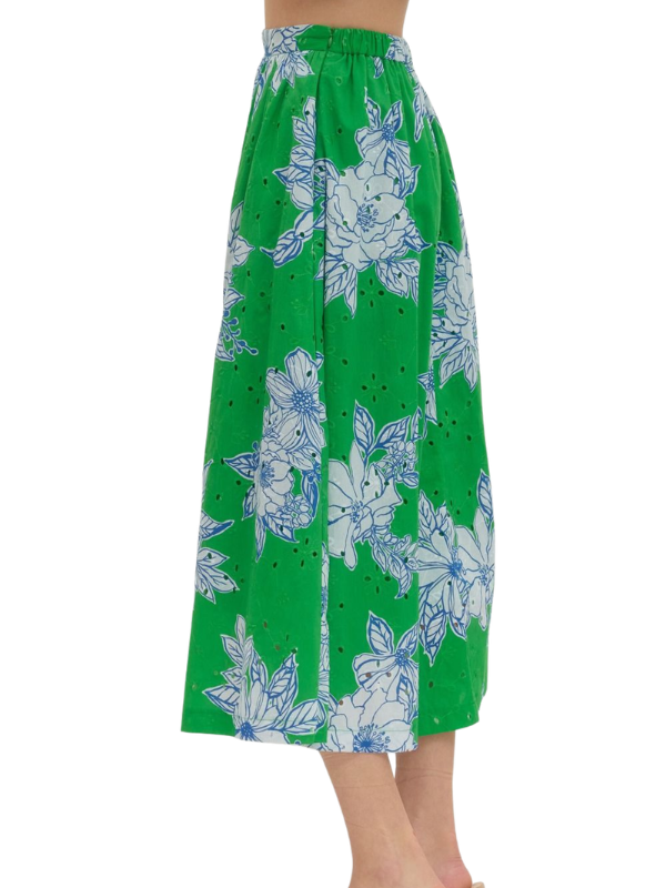 Green skirt with white floral pattern worn by a person on a white background