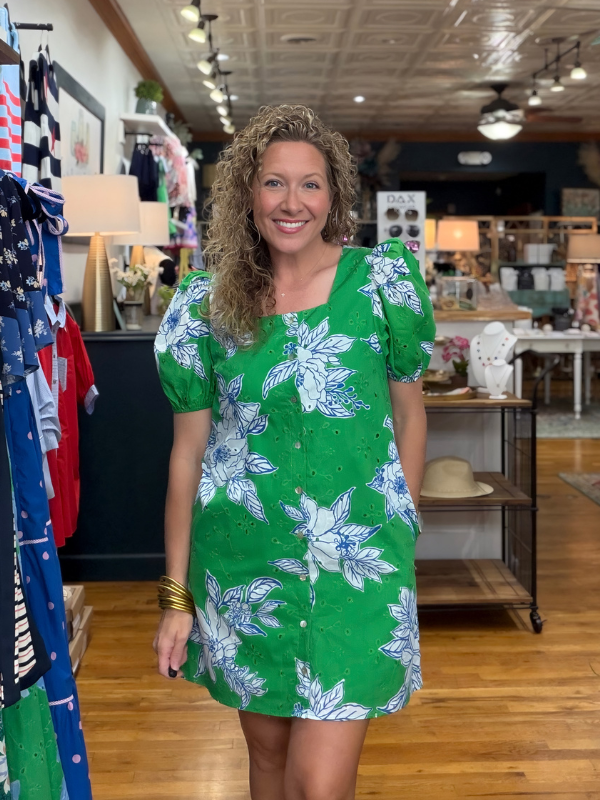 Woman wearing a green floral dress in a store setting