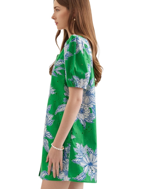 Woman wearing a green dress with floral pattern on a white background