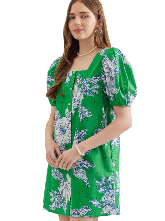 Woman wearing a green dress with white floral patterns on a white background