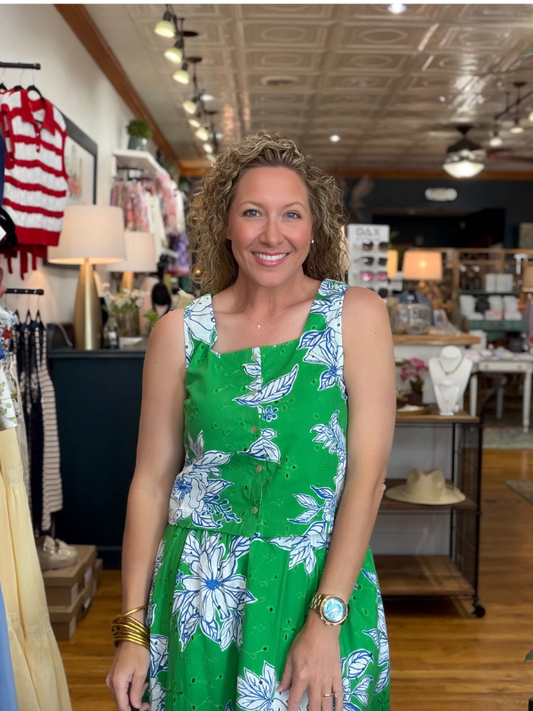 Woman in a green floral dress standing in a store.