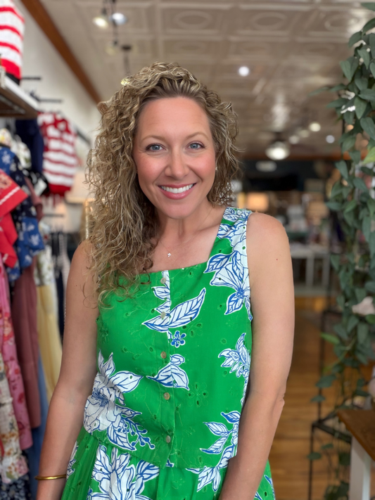 Woman wearing a green dress with floral patterns in a store setting