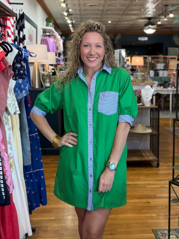Woman wearing a green dress with a striped shirt in a clothing store.