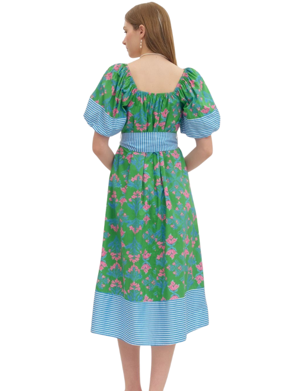 Woman wearing a green and blue floral dress with a white background
