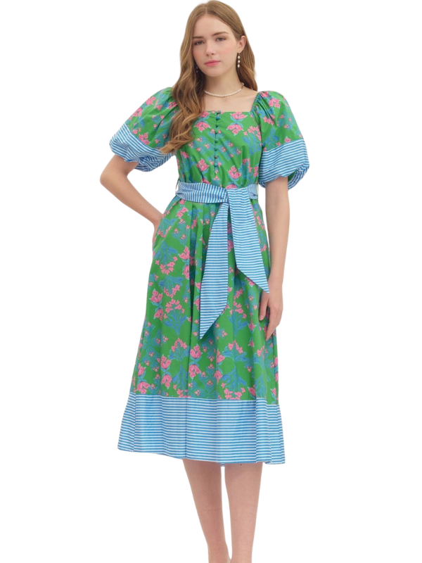 Woman wearing a green floral dress with blue accents on a white background