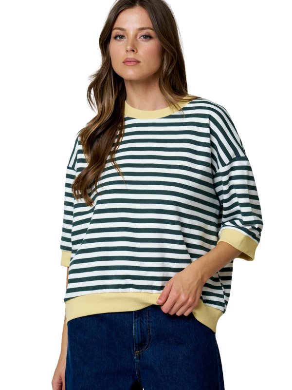 A woman wearing a green and white striped crewneck sweatshirt with yellow ribbed trim, paired with dark blue jeans, against a plain white background.