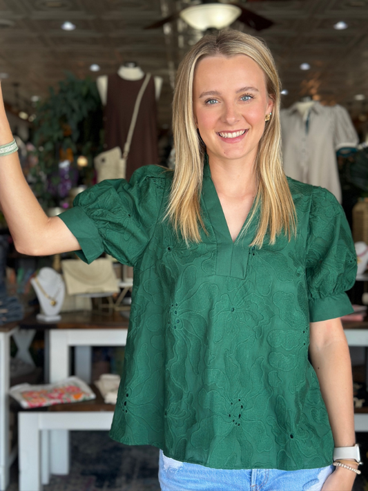 Woman wearing a green blouse in a clothing store setting