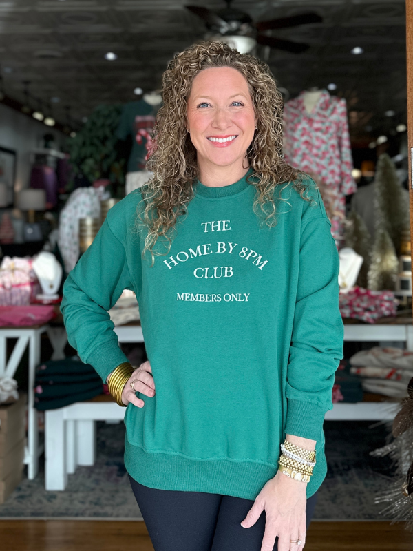 Woman wearing a teal sweatshirt with text in a casual indoor setting