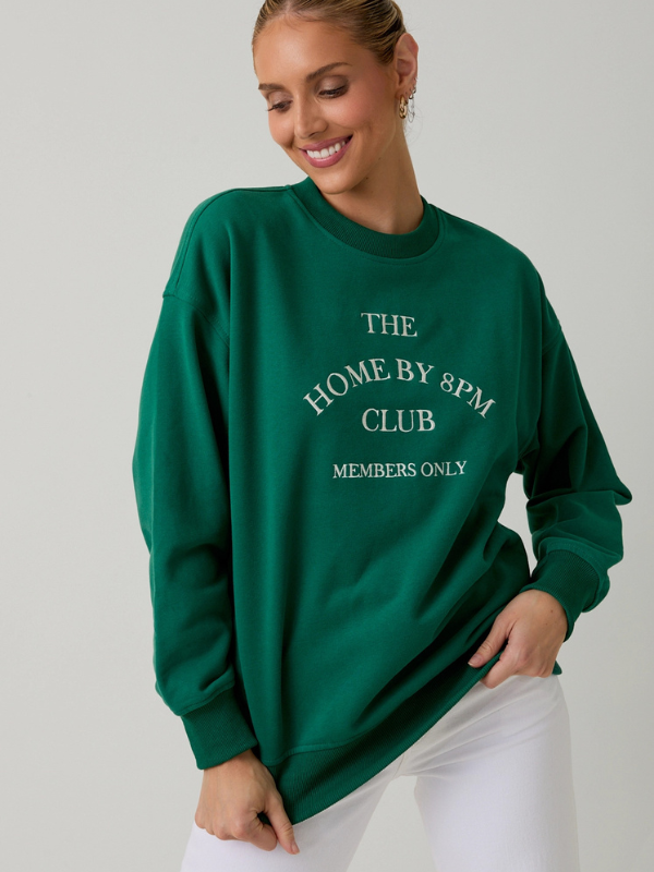 Woman wearing a green sweatshirt with text on a plain background