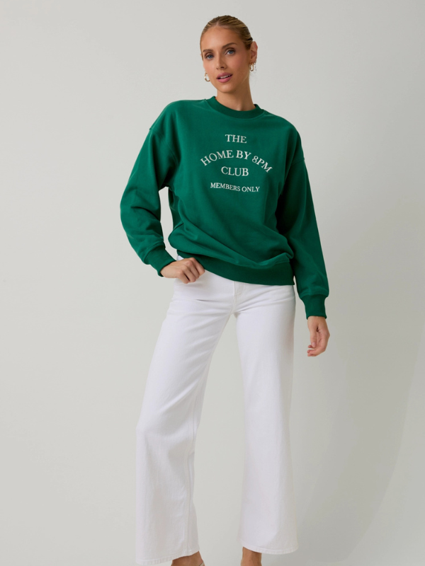 Person wearing a green sweatshirt with text on a plain background