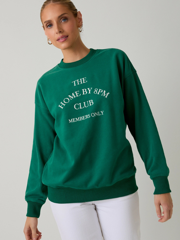 Person wearing a green sweatshirt with text on a plain background