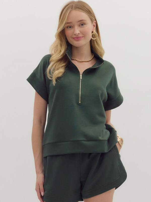 Woman wearing a green outfit with a zipper on a plain background