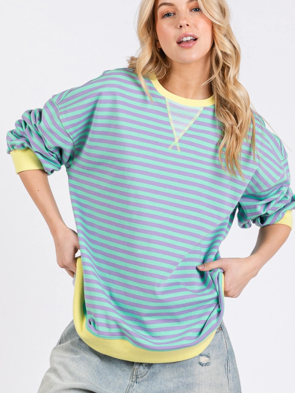 Woman wearing a green and yellow striped shirt with a plain background
