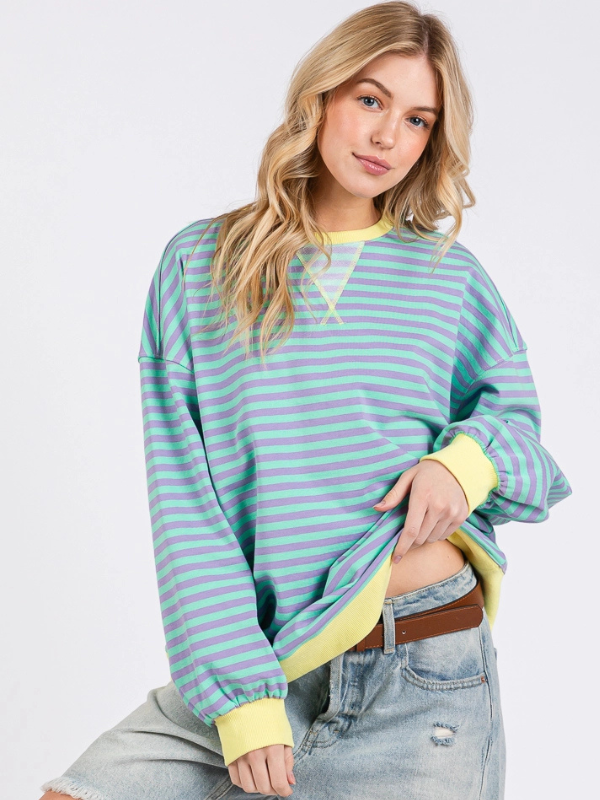 Woman wearing a striped sweater with yellow accents on a white background