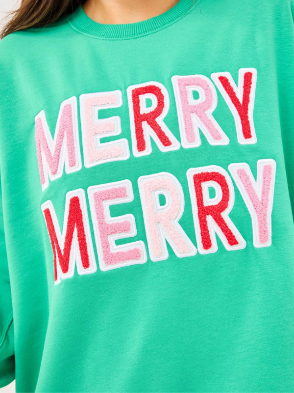 Green sweatshirt with 'MERRY MERRY' text in red and pink on a close-up view.