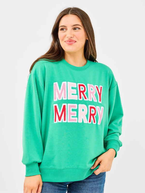 Woman wearing a green sweatshirt with 'MERRY MERRY' text on a white background