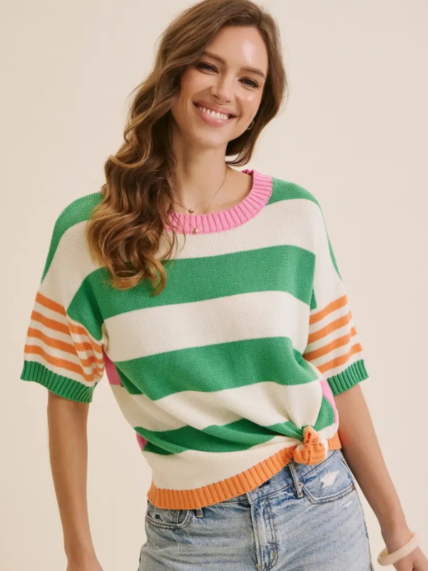 Woman wearing a colorful striped sweater with a pink collar on a beige background