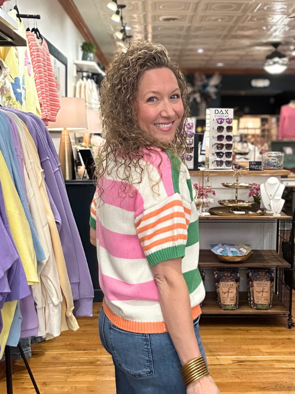 Woman wearing a colorful striped sweater in a store setting