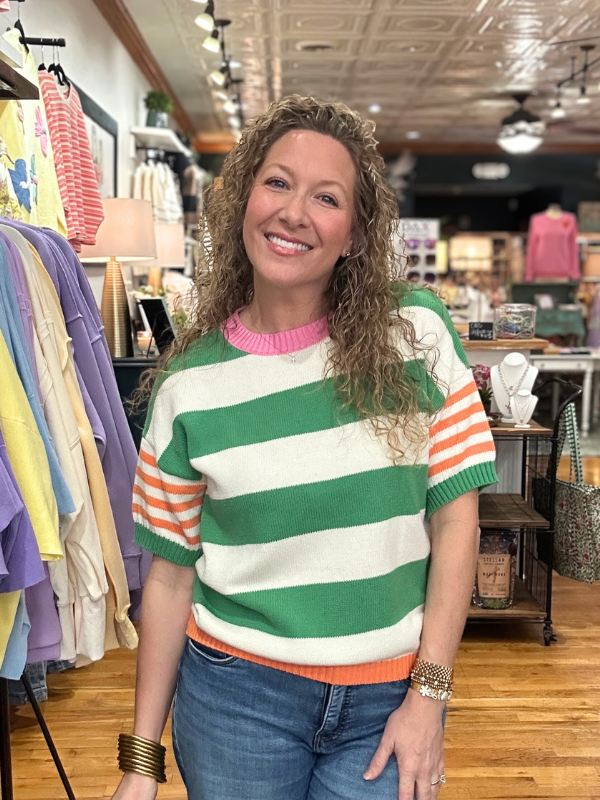 Woman wearing a colorful striped sweater in a clothing store
