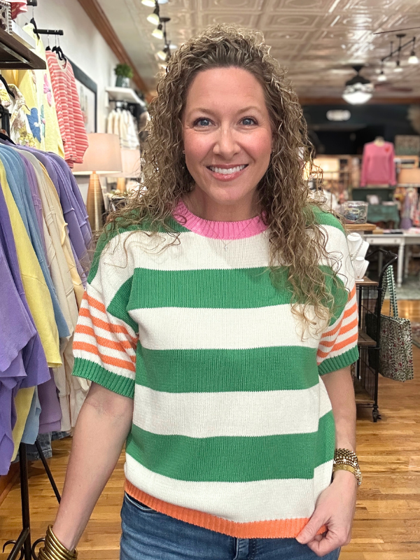 Woman wearing a green and white striped sweater in a clothing store.