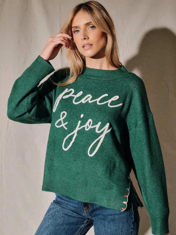 woman wearing a green peace and joy sweater 