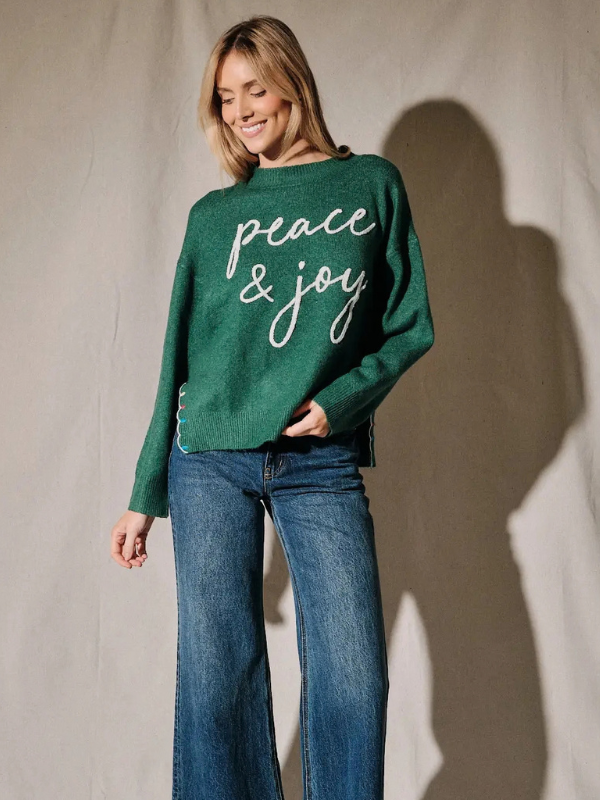 woman wearing a green peace and joy sweater 