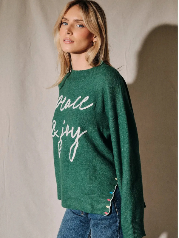 woman wearing a green peace and joy sweater 