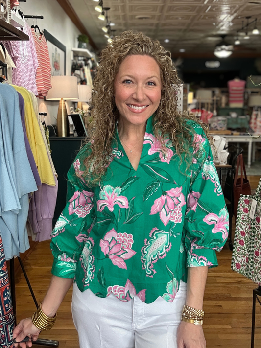 Woman wearing a green floral blouse in a clothing store