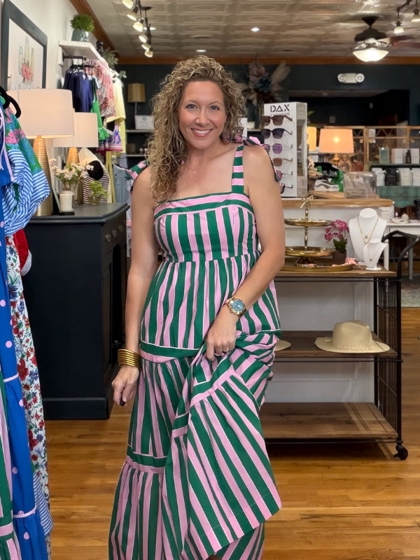 Woman in a green and pink striped dress standing in a store.