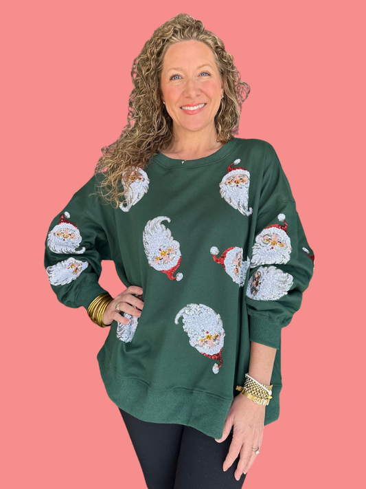 Woman wearing a green sweater with Santa Claus patterns on a pink background