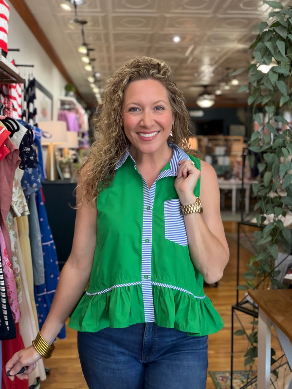Woman wearing a green sleeveless top with ruffles in a store setting