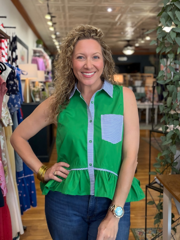 Woman wearing a green sleeveless shirt with a striped collar in a store setting