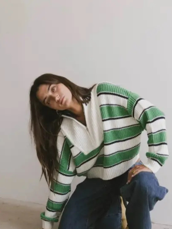 Person wearing a green and white striped sweater against a plain background