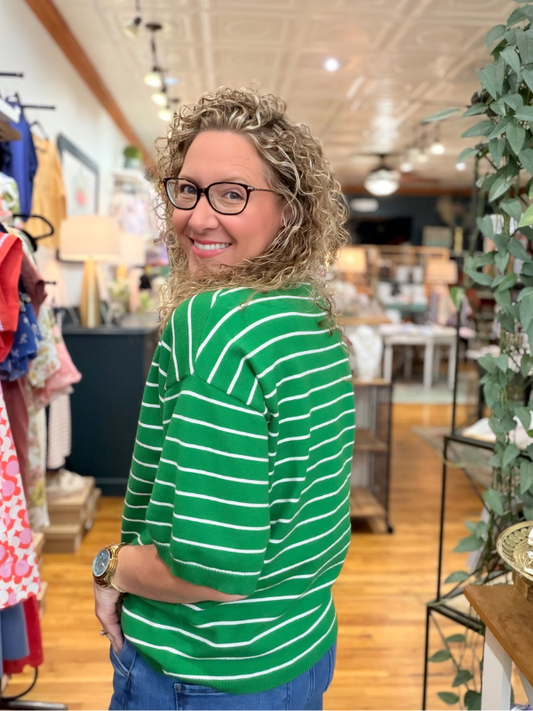 Woman wearing a green and white striped shirt in a store setting