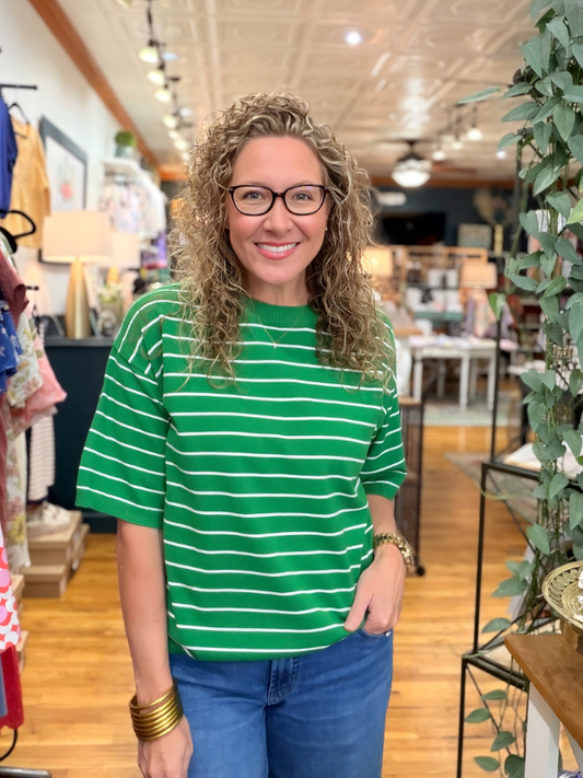Woman wearing a green striped shirt and blue jeans in a store setting