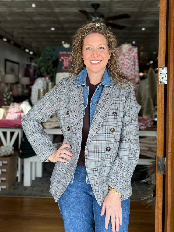 Woman wearing a plaid blazer and blue jeans in a store setting