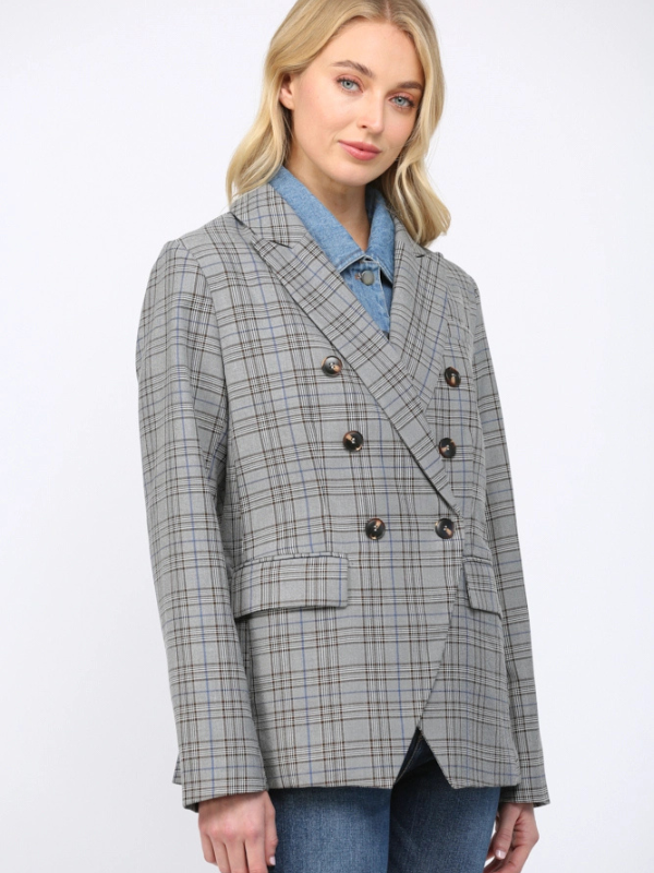 Woman wearing a gray checkered blazer over a blue shirt on a white background