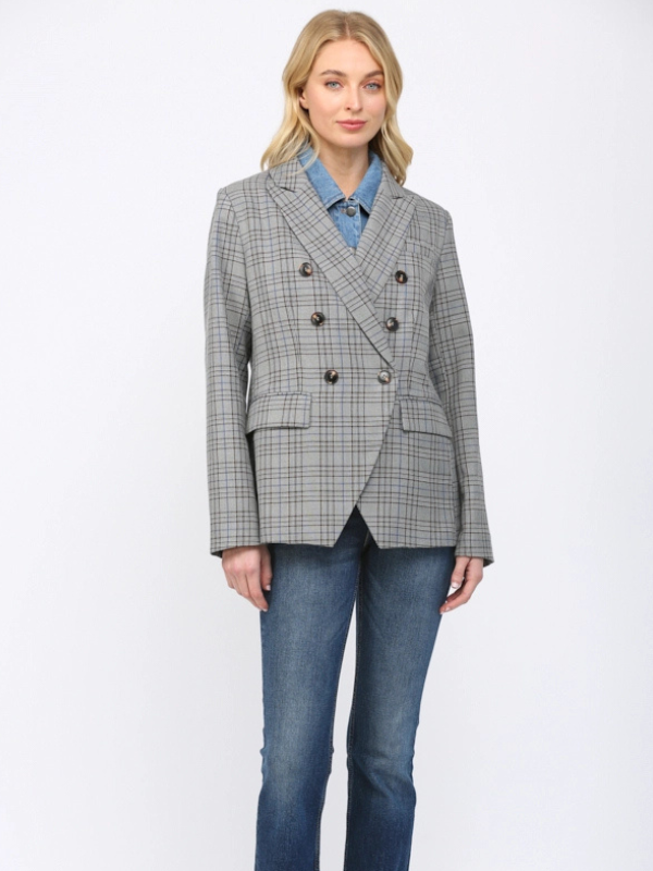 Woman wearing a gray checkered blazer over a blue shirt with jeans on a white background