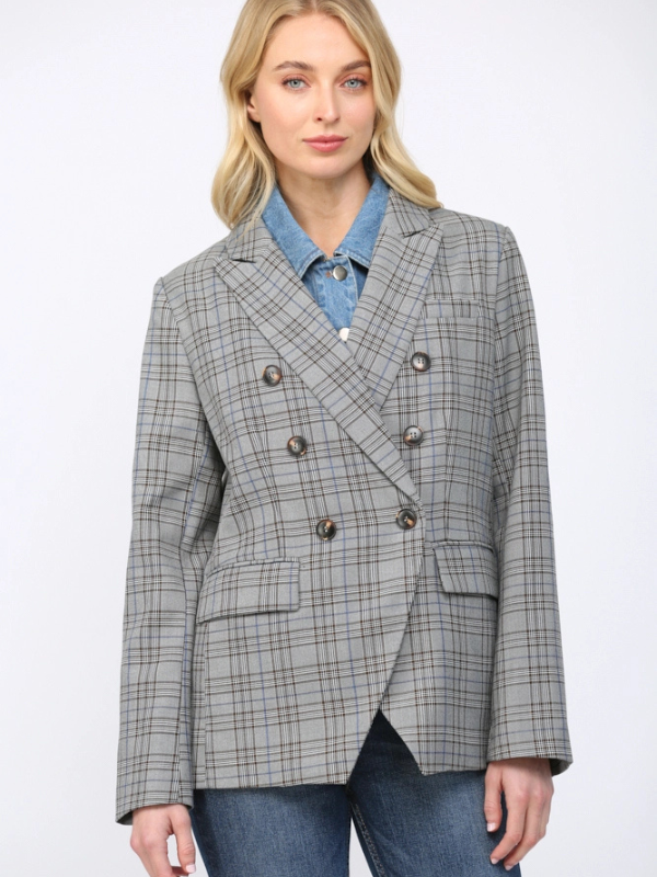Woman wearing a gray checkered blazer over a blue shirt on a white background