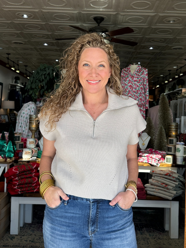 Woman standing in a store with clothing and decor items around her