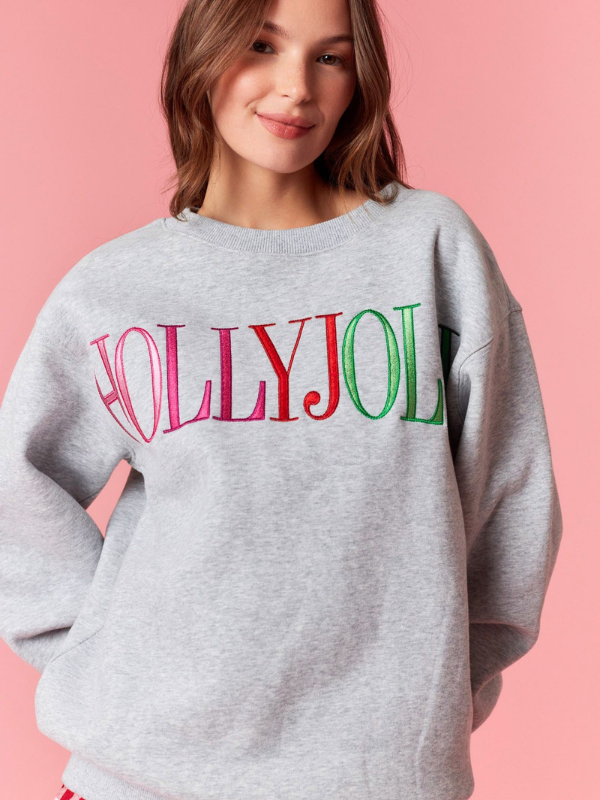 Person wearing a gray sweatshirt with 'HOLLYJOL' text on a pink background