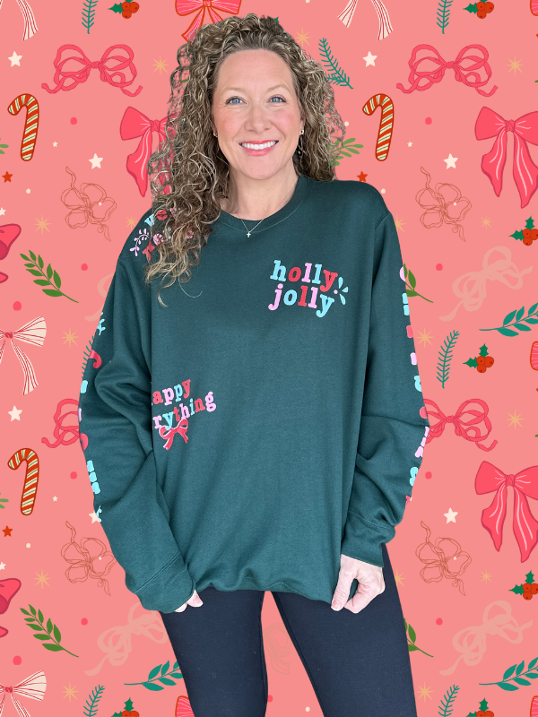 Person wearing a teal sweater with 'holly jolly' and 'happy everything' text on a festive background