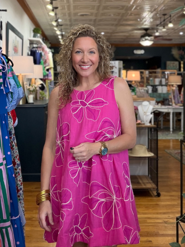 Woman wearing a pink dress with white floral patterns in a store setting