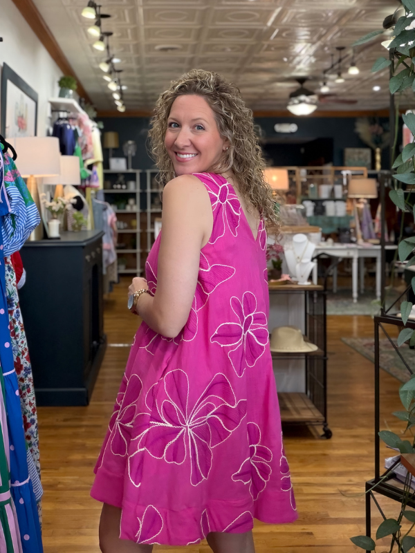 Woman wearing a pink dress with floral patterns in a store setting
